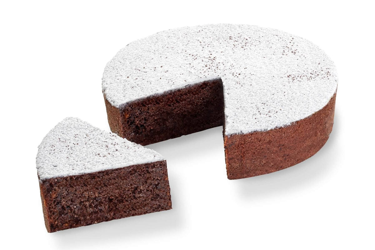 Torta Caprese Rivisitata di Iginio Massari Alta Pasticceria: presentata con una fewtta tagliata per mostrare il ripieno al cioccolato e mandorle finemente macinate, profumato alla vaniglia e ricoperto di zucchero a velo e cacao